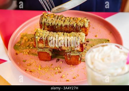 französischer Zimt-Toast mit Pistazienbelag, serviert mit Milchshake in einem schicken Café-Restaurant. Stockfoto