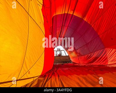 In einem farbenfrohen gelben und roten Heißluftballon, während er vorbereitet wird. Korb an der Öffnung des Ballons. Alice Springs, Australien. Stockfoto