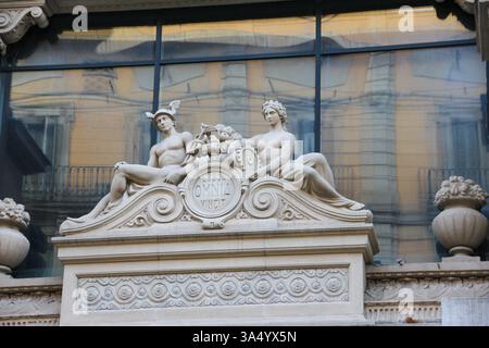 Neoklassizistische Marmorskulptur von zwei Figuren mit der lateinischen Inschrift 'Labor Omnia Vincit' an einer historischen europäischen Gebäudefassade. Stockfoto