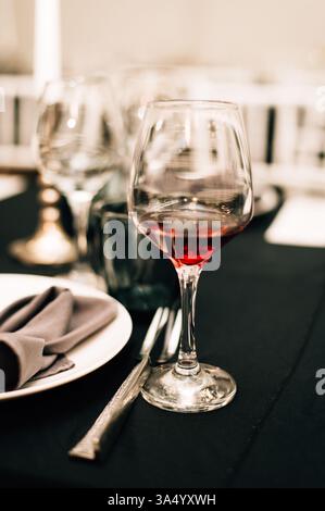 Ein Glas Rotwein auf einer schwarzen Tischdecke. Hochwertige Fotos Stockfoto