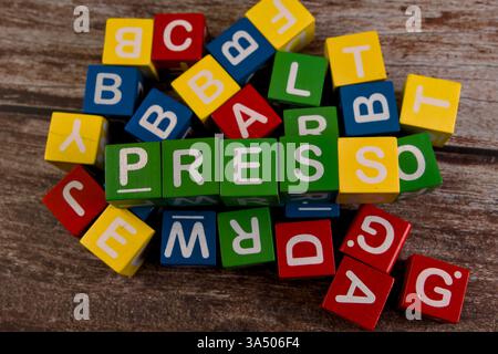 Bunte Buchstabenblöcke sind verstreut und heben neben anderen Buchstaben das Wort „Press“ hervor. Stockfoto