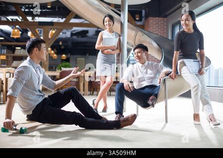 Junger chinesischer Geschäftsmann, der in einem Büro spricht und Teamarbeit und professionelle Zusammenarbeit veranschaulicht. Dieses moderne Image am Arbeitsplatz ist ideal für Unternehmenskommunikation, Meetings und Branding im Büro. Geeignet für Artikel über Teamarbeit und moderne Geschäftsumgebungen. Stockfoto