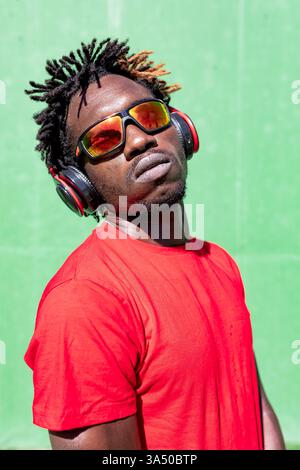 Black man Athlet hört Musik in Kopfhörern und bereitet sich auf das Training im Sommer vor Stockfoto