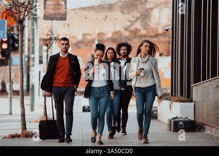 Vielfältige Gruppe junger Berufstätiger, die eine Kaffeepause machen, Kaffee trinken und mobile Geräte nutzen. Sie sind in Geschäftskleidung in einer urbanen Umgebung gekleidet. Ideal für Teamarbeit, Networking und Unternehmenskampagnen. Stockfoto