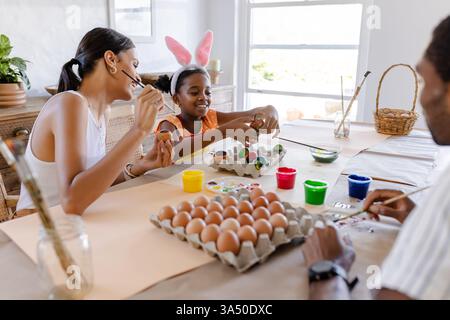 Familie, die zu Hause Ostereier malt und kreative Urlaubstätigkeit genießt Stockfoto