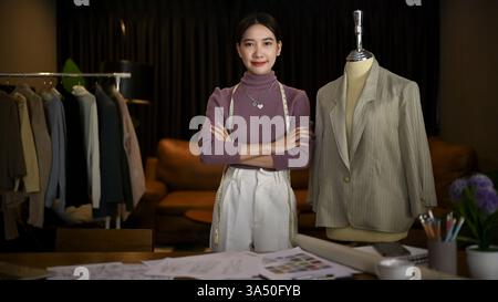 Porträt einer wunderschönen und erfolgreichen asiatischen Modedesignerin oder Schneiderin der Millennials mit gekreuzten Armen in ihrem Workshop-Studio. Kleiner Bus Stockfoto