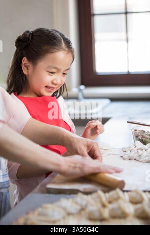 Die heitere chinesische Enkelin und Großmutter machen in der Küche Klöße. Ein herzerwärmender Moment für Familien-, Koch- und kulturelle Feierkampagnen. Ideal für Urlaube und Traditionen mit chinesischer Küche und Zweisamkeit. Stockfoto