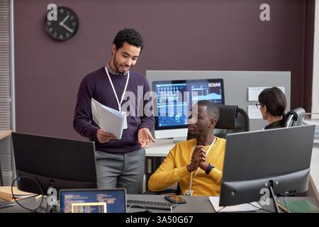 Porträt zweier Business Analytics-Experten, die ein Projekt in einem High-Tech-IT-Entwicklungsbüro diskutieren. Dieses moderne Bild am Arbeitsplatz eignet sich für Technologie, Datenanalyse, Softwareentwicklung und Visualisierungen der Unternehmensplanung. Ideal für Geschäftskommunikation, IT-Services und Kampagnen zur Teamzusammenarbeit mit vielfältiger Darstellung. Stockfoto