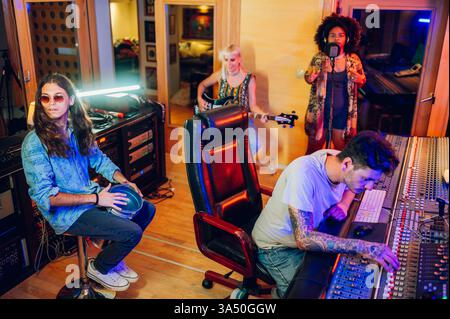 Bandaufnahmesession in einem Musikstudio mit einem männlichen Schlagzeuger mit Kelchtrommel und einem Toningenieur an der Mischkonsole. Ideal für Musik, Unterhaltung und Studioproduktionen. Authentischer, kreativer Moment in einer professionellen Umgebung. Stockfoto