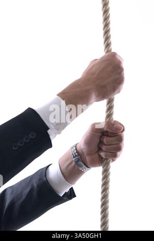 Nahaufnahme eines Geschäftsmannes aus dem Nahen Osten, der ein Seil vor einem weißen Atelierhintergrund zieht. Das Bild ruft Anstrengung, Herausforderung und Kontrolle in einem professionellen Kontext hervor. Geeignet für Geschäfts-, Führungs- und Leistungsthemen. Stockfoto