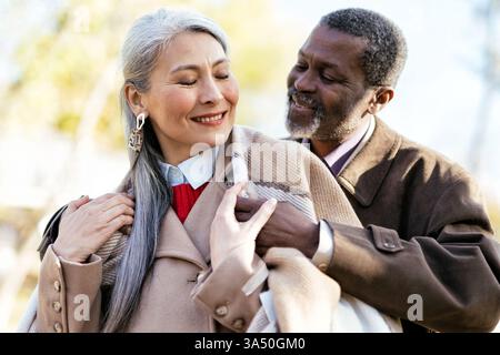 Multiethnisches Seniorenpaar, das sich einen liebevollen Moment im Freien teilt. Ein warmes, romantisches Lifestyle-Image, ideal für Ruhestand, würdevolles Altern und familiäres miteinander. Stockfoto