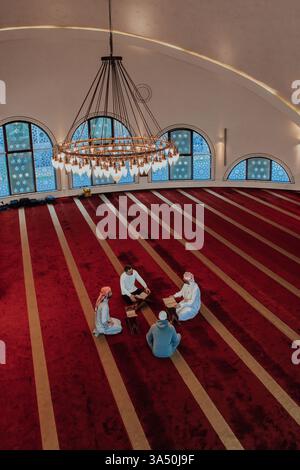 Eine Gruppe von Muslimen, die das heilige Buch des Koran in einer modernen Moschee während des muslimischen Feiertags im Ramadan lesen. Stockfoto