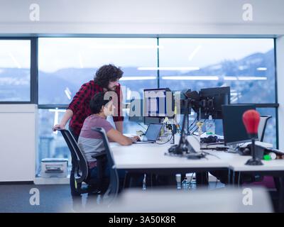 Zwei junge Softwareentwickler, die in einem modernen Startup-Büro codieren. Eine moderne Technologie- und Teamwork-Szene, die sich für geschäftliche, IT- und unternehmerische Themen eignet. Ideal für Artikel über Programmierung, Start-ups und kreative Arbeitsbereiche. Stockfoto