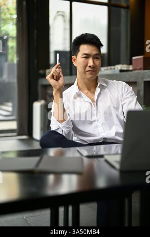 Porträt eines intelligenten und erfolgreichen asiatischen Geschäftsmanns oder männlichen Chefs, der sein Projekt plant, während er in einem Café sitzt. Stockfoto