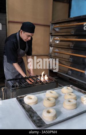 Der hispanische Bäcker zündet einen Gasherd an, bevor er Donuts in einer Bäckerei frittiert. Konzept der traditionellen mexikanischen Süßbrotzubereitung Stockfoto