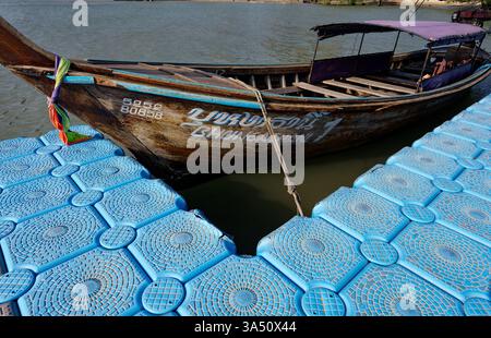 Verwittertes Langboot, das am schwimmenden Pier der East Railay ankerte und an seinem Holzrumpf Alterserscheinungen aufweist Stockfoto