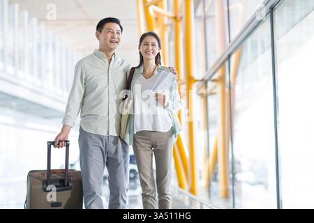 Reifes chinesisches Paar, das mit Koffer zum Flughafen ging Stockfoto