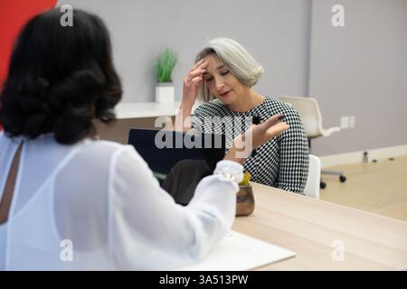 Zwei Fachleute diskutieren in einem hellen Konferenzraum. Die Szene der Bürositzungen konzentriert sich auf die Zusammenarbeit im Unternehmen, Frauen in Führungspositionen und ein vielfältiges Arbeitsumfeld. Ideal für Unternehmenskommunikation, professionelle Services und Teamwork-Kampagnen. Stockfoto