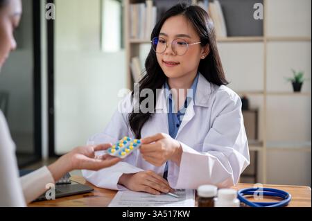 Asiatische Ärztin zeigt und verschreibt Pillen für weibliche Patienten während der medizinischen Untersuchung in der Klinik Stockfoto