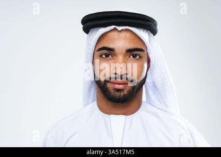 Porträt eines hübschen Mannes aus dem Nahen Osten, der eine traditionelle Kandora in einem Studio trägt. Ein poliertes Emirat-Porträt, das für Dubai, die VAE und islamische Kulturthemen geeignet ist. Stockfoto