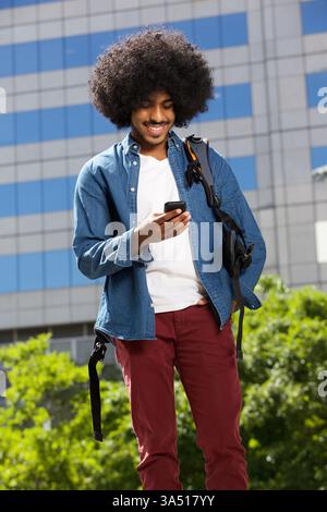 Porträt eines coolen Reisemannes, der durch die Stadt geht, während er mit einem Mobiltelefon spricht. Lässiges urbanes Design und moderne Technologie sorgen für ein dynamisches Lebensgefühl auf Reisen. Ideal für Reisen, mobile Technologie und Lifestyle-Kampagnen für Jugendliche. Stockfoto