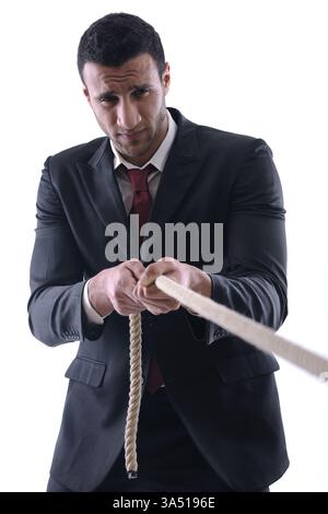 Seriöser Geschäftsmann aus dem Nahen Osten, der ein Seil auf weißem Atelierhintergrund zieht. Ein starkes Konzeptbild für Geschäfts-, Führungs- oder Stressthemen. Ideal für Unternehmenskommunikation, Kampagnen am Arbeitsplatz oder Projektmanagement-Inhalte. Stockfoto