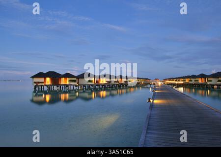 Atemberaubende Malediven Resort Szene mit tropischen Wasser Villen auf einer sonnigen Insel. Ideal für Reiseangebote, luxuriöse Kurzurlaube und tropische Urlaubskampagnen. Stockfoto