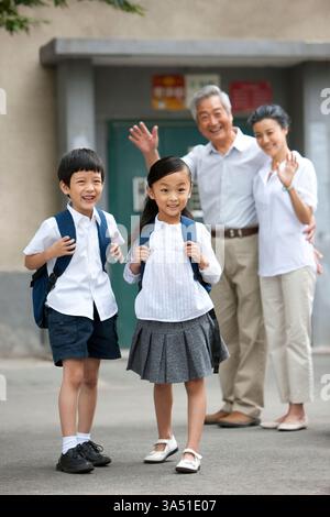 Chinesische Schüler mit Großeltern winken Stockfoto