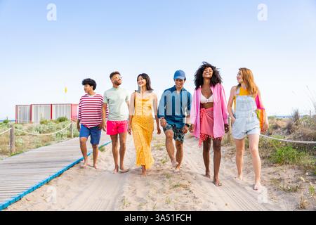 Multiethnische Gruppe junger Freunde, die sich im Sommer im Freien aufhalten, einen sonnigen Tag genießen und die Atmosphäre auf Reisen genießen. Diese lebendige Szene passt zu Lifestyle, Reisen, Jugendkultur und Gruppenaktivitäten. Ideal für Freundschaftskampagnen und gesellschaftliche Veranstaltungen im Freien. Stockfoto