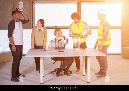 Ein vielfältiges junges Business-Team arbeitet auf einer Baustelle zusammen und überprüft Dokumente und Workflows mit einem Virtual-Reality-Headset und einem Laptop. Die Szene verbindet Arbeit vor Ort mit moderner Technologie für Planung, Design und Architektur. Geeignet für Bau-, Engineering- und Projektmanagement-Materialien. Stockfoto