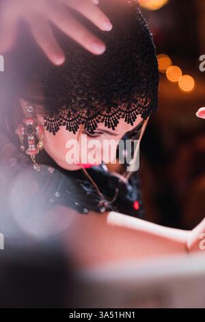 Seitenansicht einer stilvollen jungen Frau, die in einem Kleid tanzt, mit erhobener Hand und verschwommenem Hintergrund. Geeignet für Lifestyle, Tanz, Performance und kulturelle Themen. Stockfoto