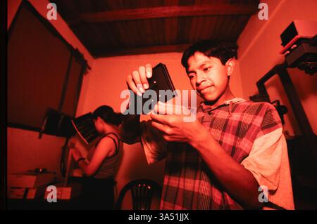 Schüler mit der „Mari Sol Photo School“ laden negative in einen größeren Negativträger in der Dunkelkammer der Schule in Guatemala City, Guatemala. Stockfoto