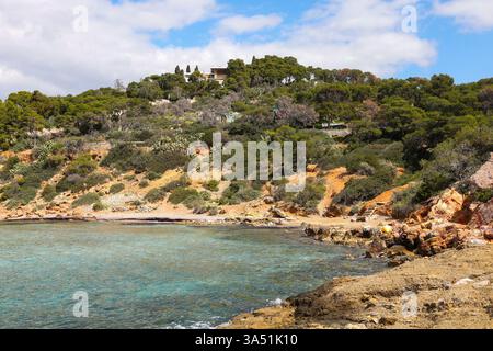 Eine abgeschiedene Bucht mit kristallklarem türkisfarbenem Wasser und zerklüfteten Klippen, umgeben von dichter mediterraner Vegetation Stockfoto
