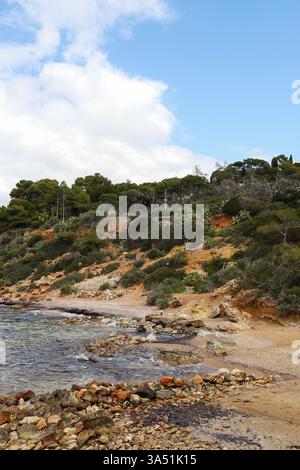 Eine abgeschiedene Bucht mit kristallklarem türkisfarbenem Wasser und zerklüfteten Klippen, umgeben von dichter mediterraner Vegetation Stockfoto