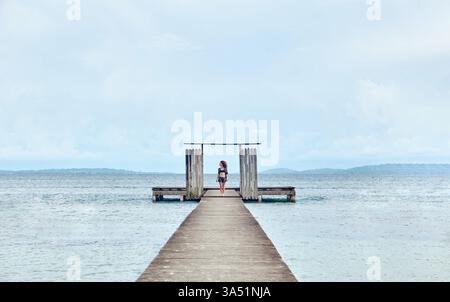 Hispanische Frau, die tagsüber auf einem Holzsteg am Strand steht Stockfoto