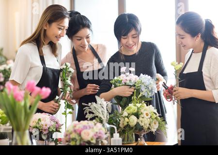 Eine chinesische Lehrerin leitet eine Blumenarrangierklasse in einer Ausbildungsschule. Die Szene zeigt Kunst- und Handwerkserziehung, Teamarbeit und kulturelle Handwerkstraditionen. Ideal für Unterrichtsräume, Workshops und kreative Lerninhalte. Stockfoto