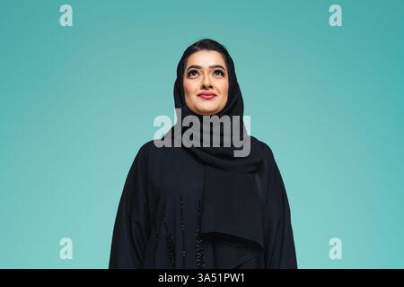Schöne arabische Frau, die eine traditionelle Abaya in einem Atelierporträt trägt. Ein raffiniertes nahöstliches Mode- und Kulturbild, das für Schönheit, Lifestyle und regionale Inhalte geeignet ist. Stockfoto