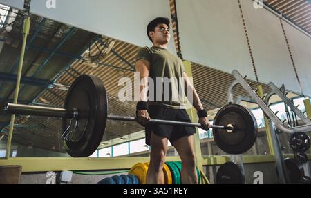 Asiatischer Mann führt einen schweren Deadlift in einem Fitnessstudio aus. Ein dynamisches Fitnessbild, das Stärke, Konzentration und Entschlossenheit betont. Ideal für Fitnesskampagnen, Trainingsprogramme und sportliches Lifestyle-Branding. Stockfoto