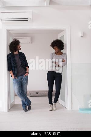Ein junges multiethnisches Paar, das eine Pause von der Renovierung macht. Sie wirken fröhlich und betonen Teamwork und Hausleben. Ideal für Wohnraumgestaltung, Familienleben und Innenarchitektur. Stockfoto