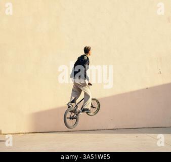 Ein schwarzer männlicher Fahrer führt einen BMX-Trick in einem Skatepark der Stadt aus. Dynamische urbane Freestyle-Szene mit sportlichem Können und Jugendkultur. Ideal für Extremsportarten, Straßensport und urbane Lifestyle-Bilder. Stockfoto