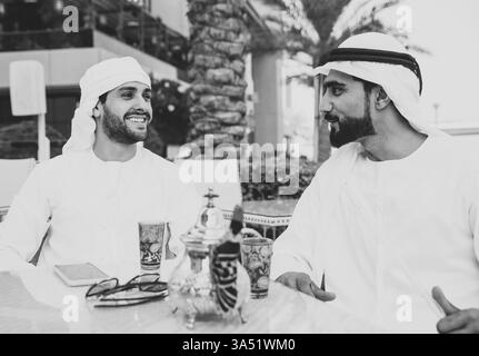 Zwei junge Unternehmer Ausgehen in Dubai. Freunde tragen Der kandura traditionelle männliche Outfit in Marina Stockfoto