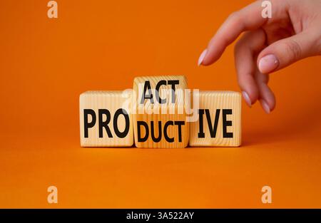 Proaktives und produktives Symbol. Geschäftsmann-Hand zeigt auf gedrehte Holzwürfel mit Worten produktiv und proaktiv. Wunderschöner orangefarbener Hintergrund. Busi Stockfoto