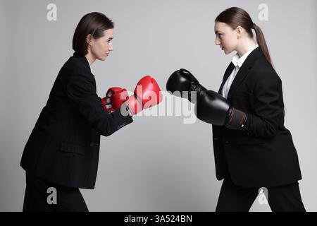 Wettbewerb. Geschäftsfrauen im Handschuhboxen auf grauem Hintergrund Stockfoto