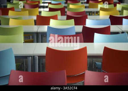 Leere Sitzreihen mit Tischen und bunten Stühlen im Raum einer Bildungseinrichtung oder Schule Stockfoto
