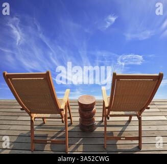 Der komfortable Ort, um die Schönheit der Wolken in Patagonien zu genießen. Zwei zusammenklappbare Holzstühle und ein kleiner Nachttisch auf der Promenade Stockfoto