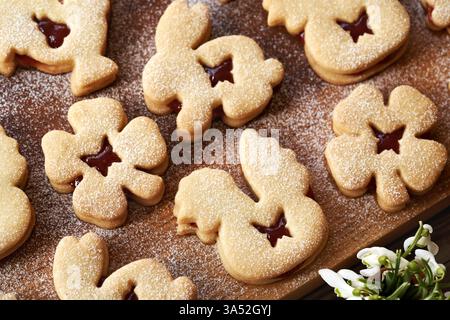 Hausgemachte Linzer Osterkekse gefüllt mit Marmelade und mit Zucker auf einem Holzbrett bestäubt Stockfoto