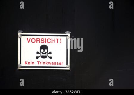 Ein Warnschild mit Schädel und Kreuzknochen und rotem Schriftzug auf schwarzem Hintergrund Stockfoto