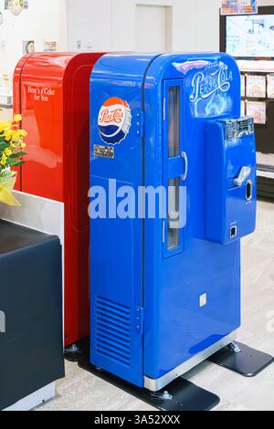 Osaka, Japan - 25. September 2024, vertikal, Nahaufnahme zweier antiker Soda-Automaten, blau und rot, Coca-Cola und Pepsi-Cola Firmen, in einem Einkaufsviertel Stockfoto