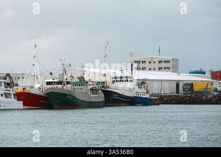 Reykjavik, Island - 4. April 2017: In einem Industriehafen liegen Fischerboote verschiedener Größe vor, im Hintergrund befinden sich Lagergebäude Stockfoto