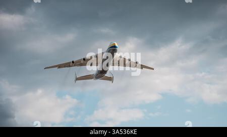 An-225 gewinnt an Höhe und hinterlässt Rauchspuren. Ich schaue auf das riesige Mriya-Frachtflugzeug vor dunklen Wolken. Stockfoto